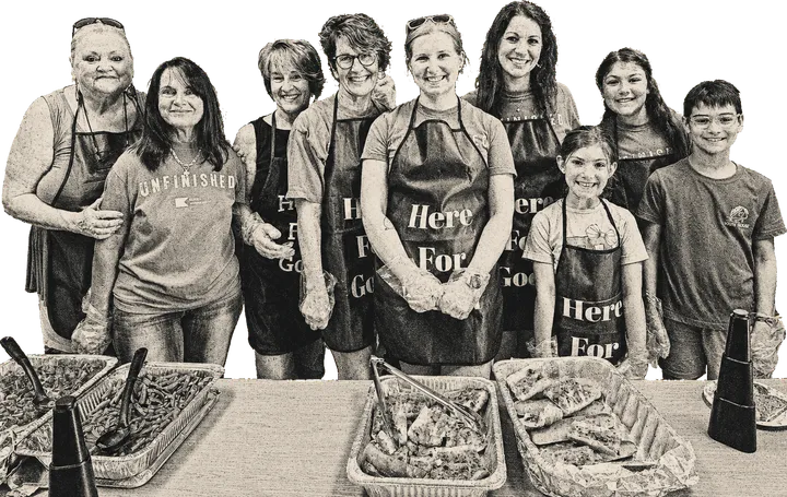 Volunteers in Here for Good aprons serving a meal